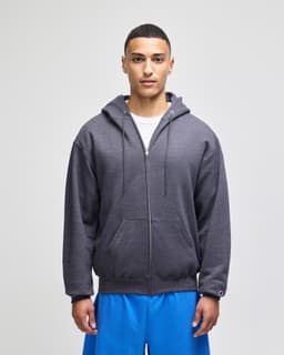A grey full-zip hooded sweatshirt worn by a model, paired with blue shorts. The sweatshirt features a logo.