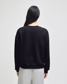 A black women's crewneck sweatshirt with a loose fit, featuring long sleeves and a simple design.