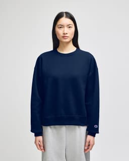 A navy blue women's crewneck sweatshirt with a relaxed fit and a branding logo on the sleeve.