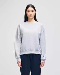 A grey women's crewneck sweatshirt with a casual fit, featuring long sleeves and a branded logo.