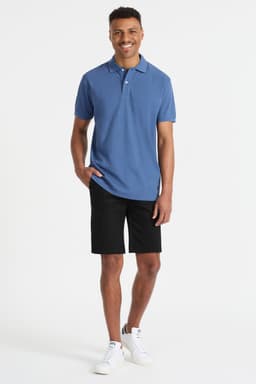 A man wearing a blue polo shirt and black shorts, paired with white sneakers. The shirt features a logo.