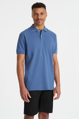 A young man wearing a blue polo shirt paired with black shorts, featuring a small logo.