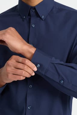 A dark navy men's long sleeve button-up shirt featuring a neat collar and button detail on the cuffs.