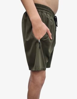 Sports shorts in olive green with an elastic waistband and pockets. Features a logo on the leg.