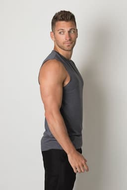 A grey singlet shirt is worn by a young man, showcasing a fitted design. The shirt features a logo.