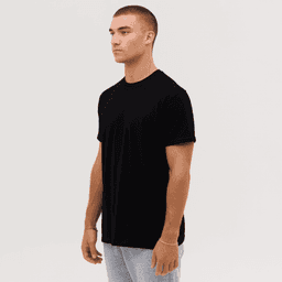 A black T-shirt displayed on a male model standing in profile against a plain background. Features a branding logo.