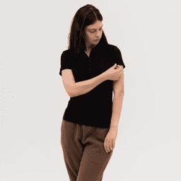 A black women's polo shirt is featured, styled with a relaxed fit and short sleeves. It has a logo on the side.