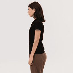 A black women's polo shirt displayed on a model, featuring a simple design and short sleeves.