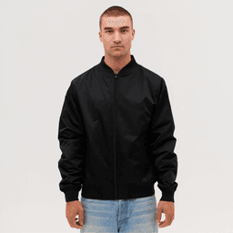 A black bomber jacket worn by a model, featuring a zip front and ribbed cuffs. The model has short hair and is standing against a neutral background.