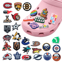 A pink shoe adorned with various colourful PVC charms, featuring different sports team logos and playful designs.