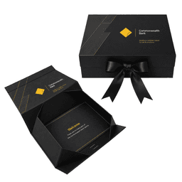 A large black gift box with a gold geometric design and black ribbon, featuring an interior greeting card.