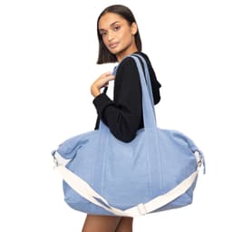 A blue duffle bag with a white shoulder strap, held by a model wearing a black hoodie. The bag has a branding logo.