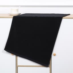 A black gym towel laid flat on a light wooden surface, featuring a clean design with a simple border.