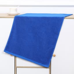 A blue gym towel is draped over a shelf, with a cup and saucer positioned beside it. The towel has a neat trim.