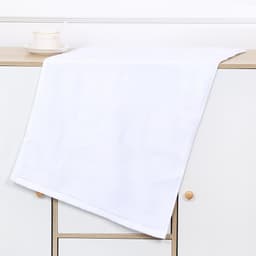 A white gym towel draped over a wooden surface, featuring a simple design with a logo.