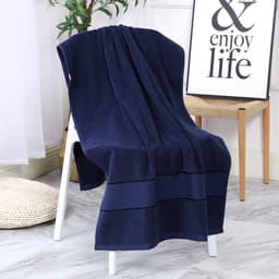 A navy blue bath towel draped over a white chair, with a decorative sign and plant in the background.