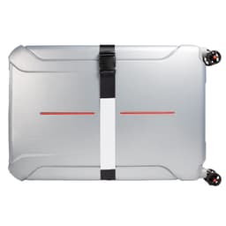 A luggage strap secures a silver suitcase, featuring a minimalistic design with a central white stripe and red accents.