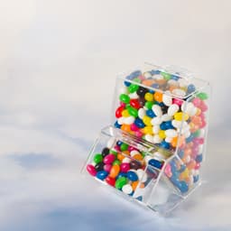 A clear dispenser filled with assorted coloured mini jelly beans, featuring vibrant hues of red, blue, green, yellow, and white.