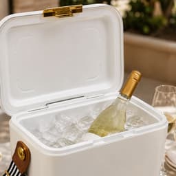 A white cooler filled with ice and a bottle of wine, featuring a gold latch and a striped handle.
