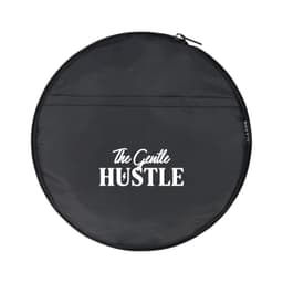 A round black bag with a zip, featuring a logo and the words "The Gentle Hustle" in white.