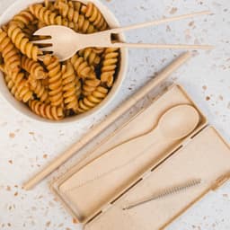 A Ramen Cutlery Set featuring bamboo fork, spoon, chopsticks, and a cleaning brush, presented with a bowl of fusilli pasta.
