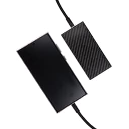 A smartphone connected to a charging cable with a sleek, carbon fiber design power bank.