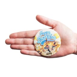 A hand holds a colourful 75mm round magnet featuring a birthday design and a logo at the bottom.