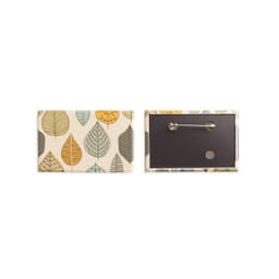 A rectangular badge featuring a multi-coloured leaf design on the front and a black backing with a pin.