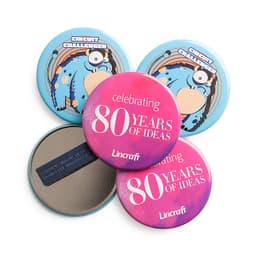 Four round badge magnets in vibrant blue and pink with various designs, including a logo and text about celebrating ideas.