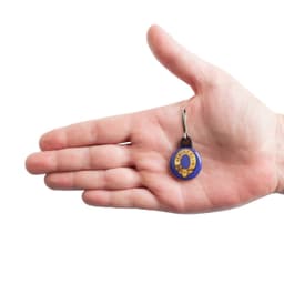 A hand holding a custom printed 25mm round zipper pull in purple and yellow, featuring a logo.