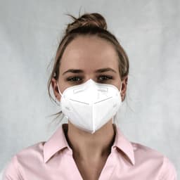 A white N95 respirator face mask worn by a person, featuring a logo and a plain background.