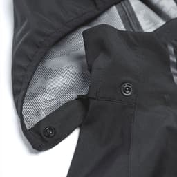 A softshell jacket featuring a black exterior and a patterned grey interior, with visible snaps and a hood.