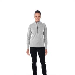 A woman wearing a grey knitted half zip jumper, smiling against a plain background. The jumper has a logo on it.