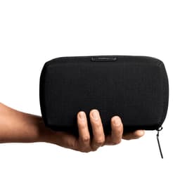 A black tech kit held in a hand, featuring a zip closure and a branding logo.