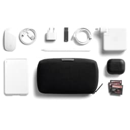 A black tech kit surrounded by a white power bank, mouse, charging cables, a stylus, AirPods, and a USB drive.