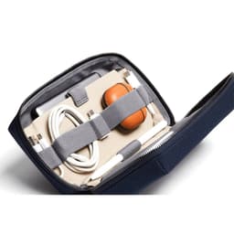 A navy tech kit containing a stylus, cables, and a case for earbuds, secured with elastic straps inside.
