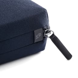 A close-up of a navy blue tech kit with a textured surface and a zip fastening, featuring a small logo.