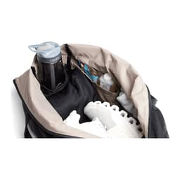 A black duffel bag opened to reveal a drink bottle, athletic shoes, and various smaller items inside.