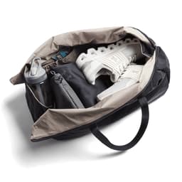 A black and beige duffel bag containing a water bottle, shoes, and a grey pouch. The bag has a logo.