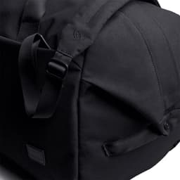 A black duffel bag featuring adjustable straps and a sleek design, with a logo on the side.