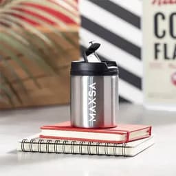 A drink bottle in silver stainless steel with a black lid, resting on top of two notebooks, with a logo displayed.