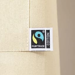 A close-up of a cream-coloured apron featuring a Fairtrade cotton label and a logo.