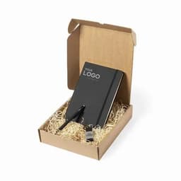 A gift box featuring a black notebook, pen, and a keychain, all set in shredded paper. The box has a logo on it.