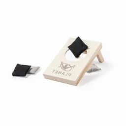 A cornhole game set featuring a wooden board with a hole and two small bags in black and grey. The board has a logo.