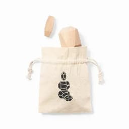 A drawstring canvas bag containing two wooden pieces, one shaped like a crystal, in a natural colour.