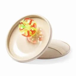A toy ball sitting on a beige plate, featuring bright yellow, orange, and green colours with a circular design.