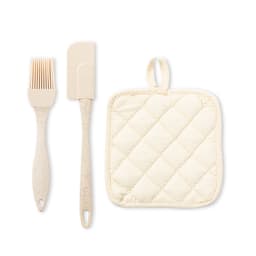 A kitchen set featuring a pale beige silicone brush, a spatula, and a cream quilted pot holder.