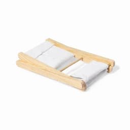 A wooden bed frame with two white cushions, designed for a miniature or decorative display.