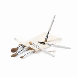 A makeup brush set displayed on a natural fabric pouch, featuring various brushes with white handles and silver ferrules.