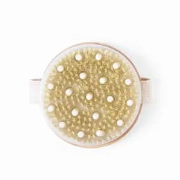 A round body brush with a textured golden bristle surface and small white beads, featuring a fabric strap.